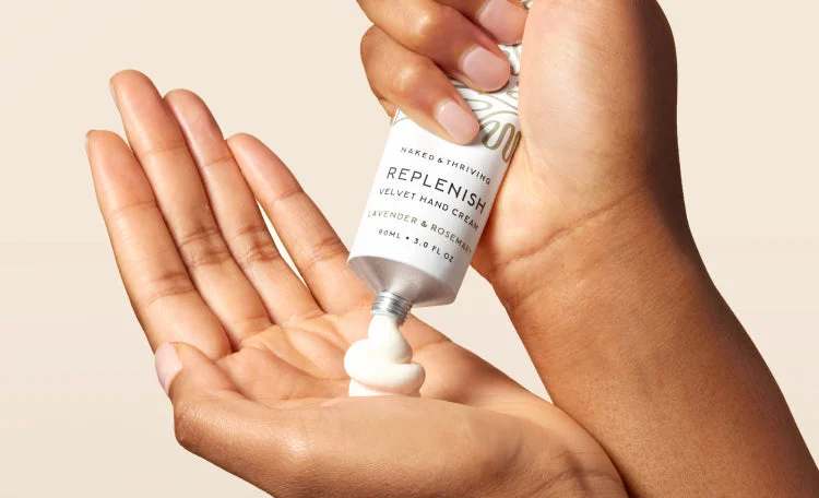Hands with a tube of Replenish Velvet Hand Cream squeezing cream into a palm