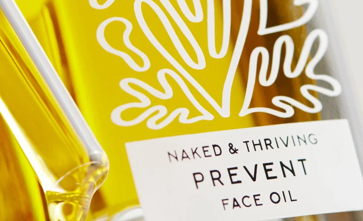 Close-up of the Prevent Face Oil label on a glass bottle of golden oil