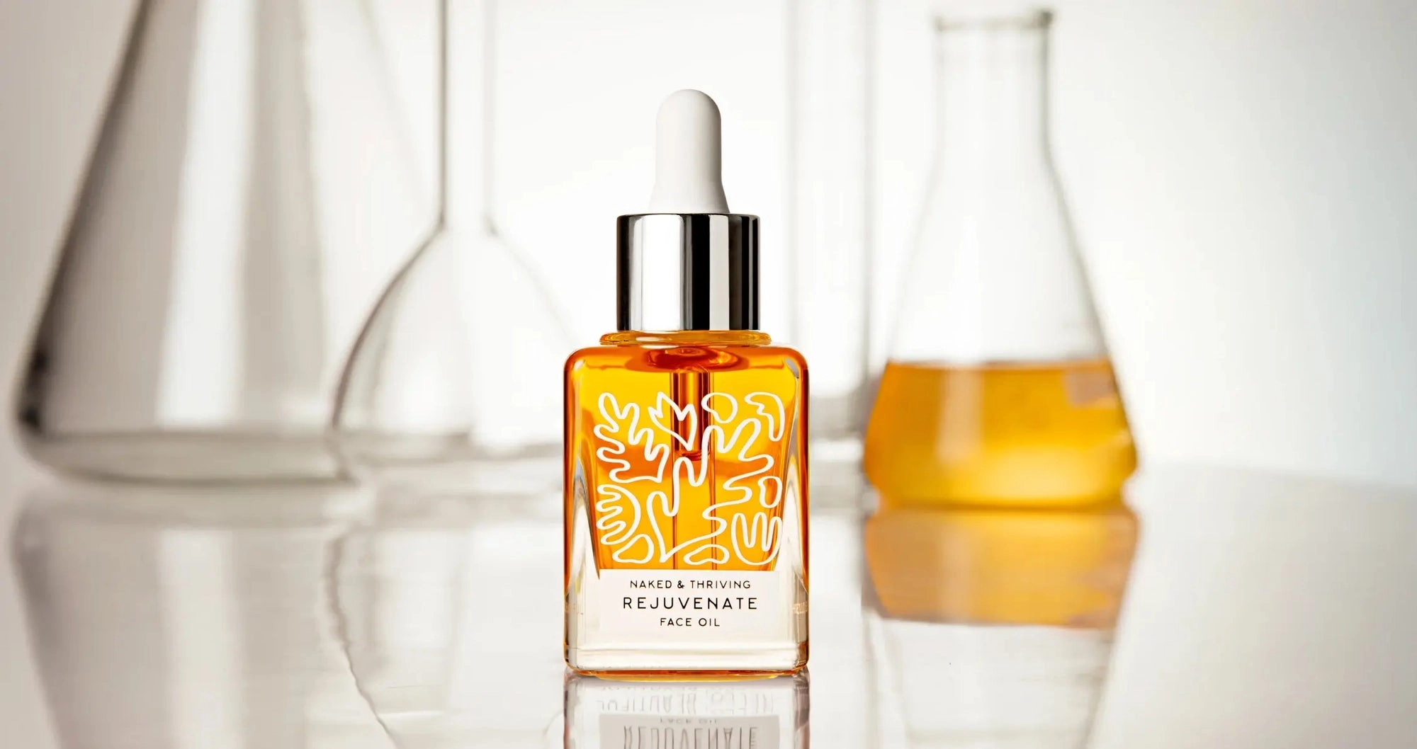 Rejuvenate Face Oil dropper bottle among laboratory glassware